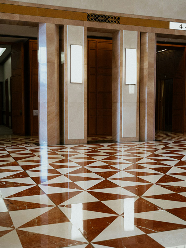 Hotel lobby with 2 lift doors open and luxury floor tiles