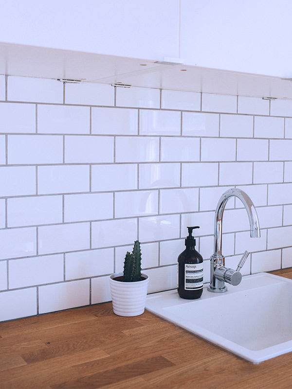 A kitchen work surface with white tiles on the wall